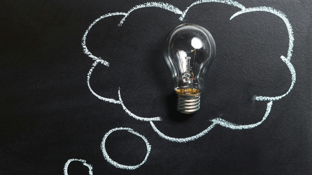 A whiteboard or chalkboard with a cloud shape drawn on it, and a glowing lightbulb depicted inside the cloud, symbolizing a brilliant new idea or innovation in the context of startup funding (bootstrapping and venture capital)