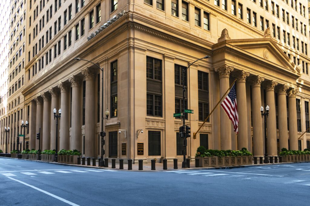 The exterior of a grand, classical building with columns, often associated with a central bank or financial institution, symbolizing authority and stability.
