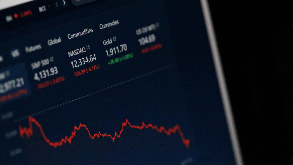A close-up of a digital stock market display showing green and red numbers and ticker symbols, representing real-time market indices data.