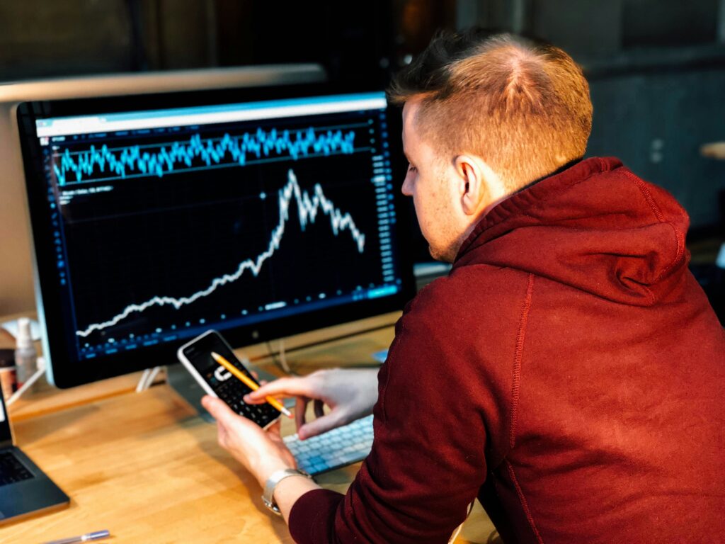 Investor analyzing stock market crash on computer screen with falling chart and calculator in hand