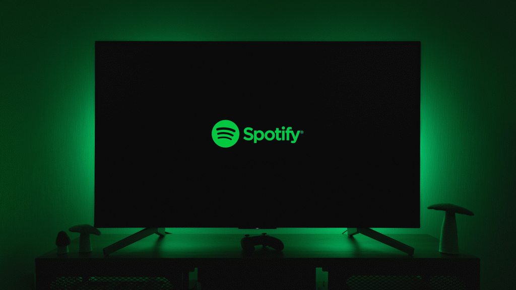 The iconic green Spotify logo glows prominently on a black screen, with a vibrant green light emanating from behind, symbolizing the digital presence and innovative spirit of leading streaming platforms.