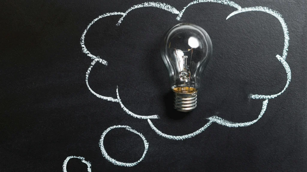 A whiteboard or chalkboard with a cloud shape drawn on it, and a glowing lightbulb depicted inside the cloud, symbolizing a brilliant new idea or innovation in the context of startup funding (bootstrapping and venture capital).