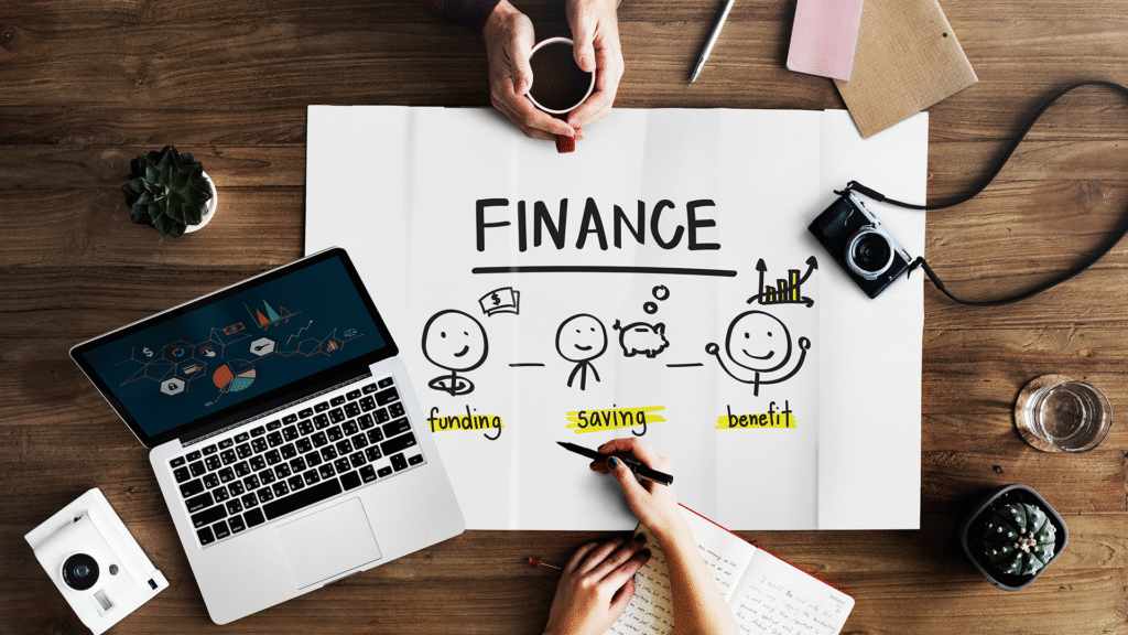 Top view of an open laptop with a financial chart, graphs, and money-related items on the desk, representing financial goals.