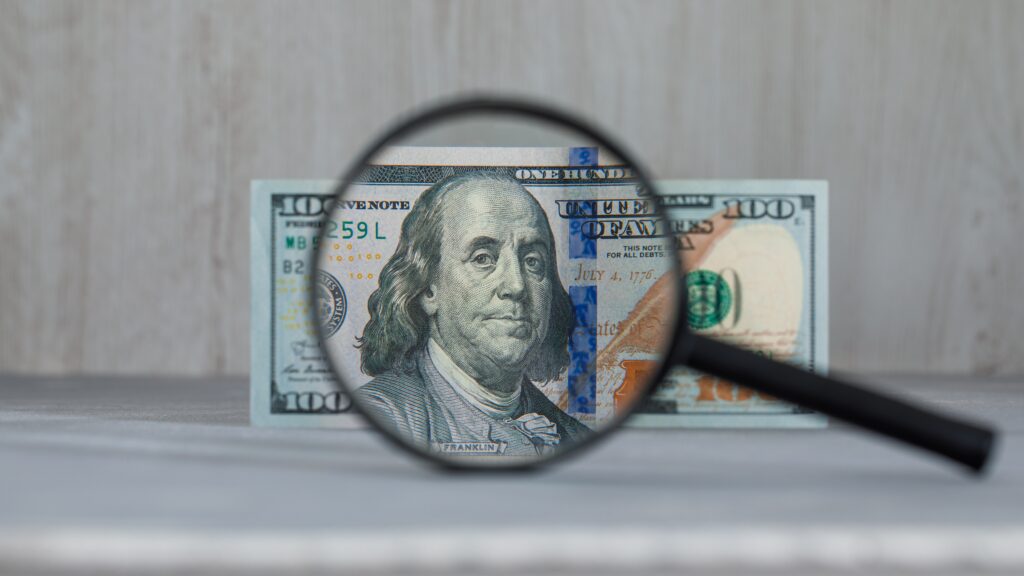 Microscope focusing on a US dollar bill, representing the psychology of money and how closely our mindset influences financial decisions.