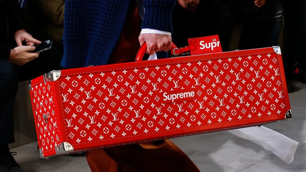 Red Louis Vuitton x Supreme trunk with monogram pattern and Supreme logo, showcased during the collaboration collection.