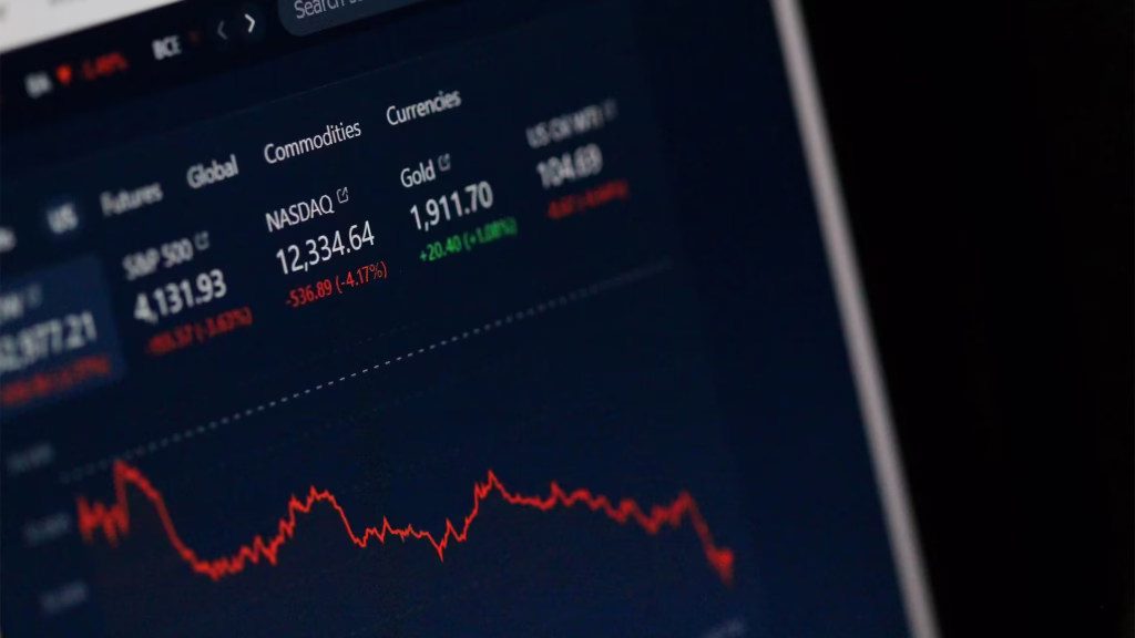 Stock market trading app screen displaying NASDAQ index at 12,334.64 with red downward trend chart, gold and currency prices, showing real-time market data and price movements explaining how stock markets function