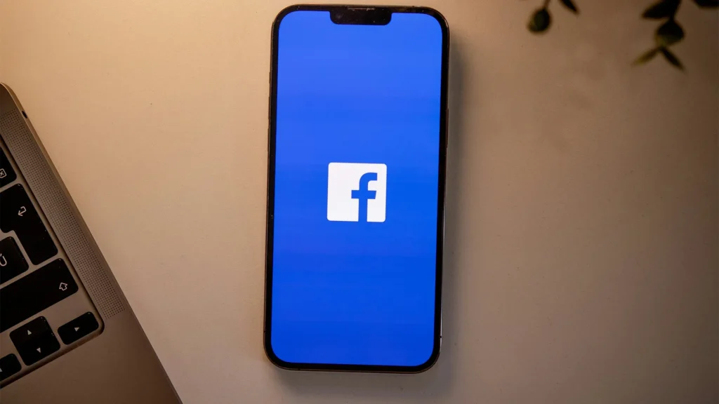 Facebook app on smartphone screen showing news feed with blue interface, representing social media algorithm that keeps users scrolling and engaged