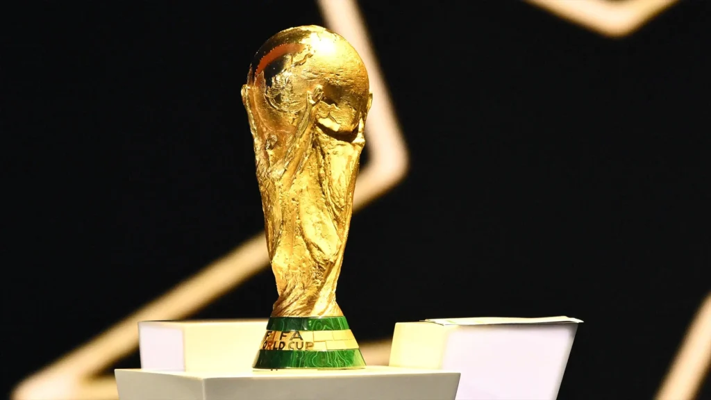 FIFA World Cup trophy on display with golden surface gleaming under stadium lights showing iconic tournament symbol