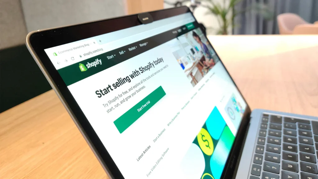 Laptop displaying Shopify ecommerce platform homepage with "Start selling with Shopify today" message showing platform strategy