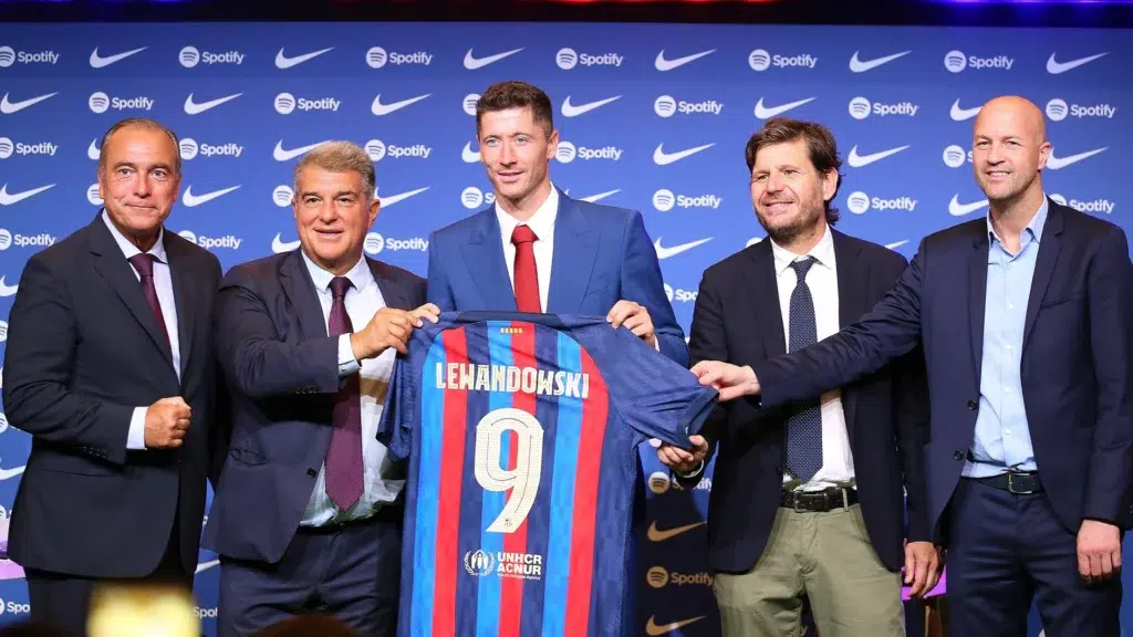 Robert Lewandowski holding Barcelona jersey with Joan Laporta at Camp Nou unveiling Barcelona financial crisis spending despite €3.5 billion debt
