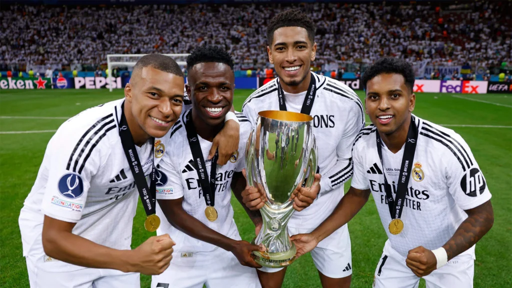 Real Madrid players Vinicius Junior Kylian Mbappe Jude Bellingham celebrating UEFA Super Cup trophy financial success smart spending