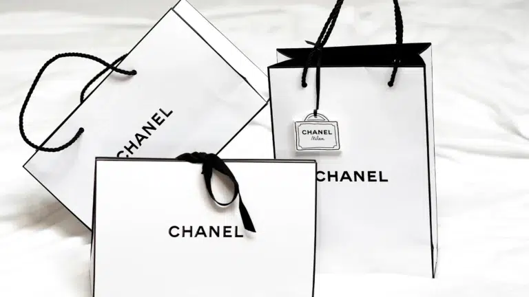 Chanel shopping bags and gift packaging in signature white with black trim showing luxury brand presentation that supports premium pricing and exclusivity perception