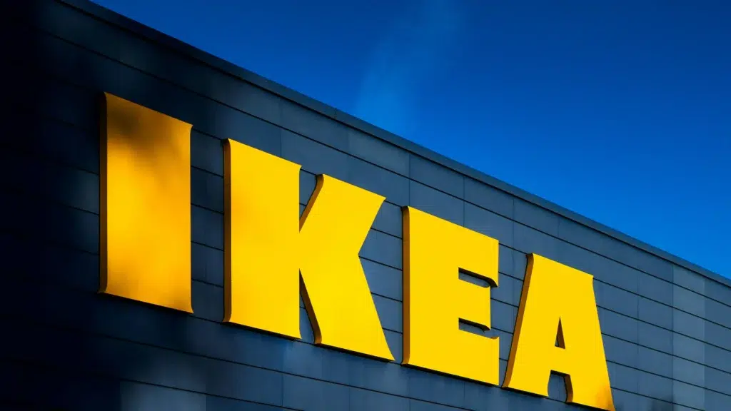 Illuminated IKEA logo signage on building exterior at dusk with blue sky