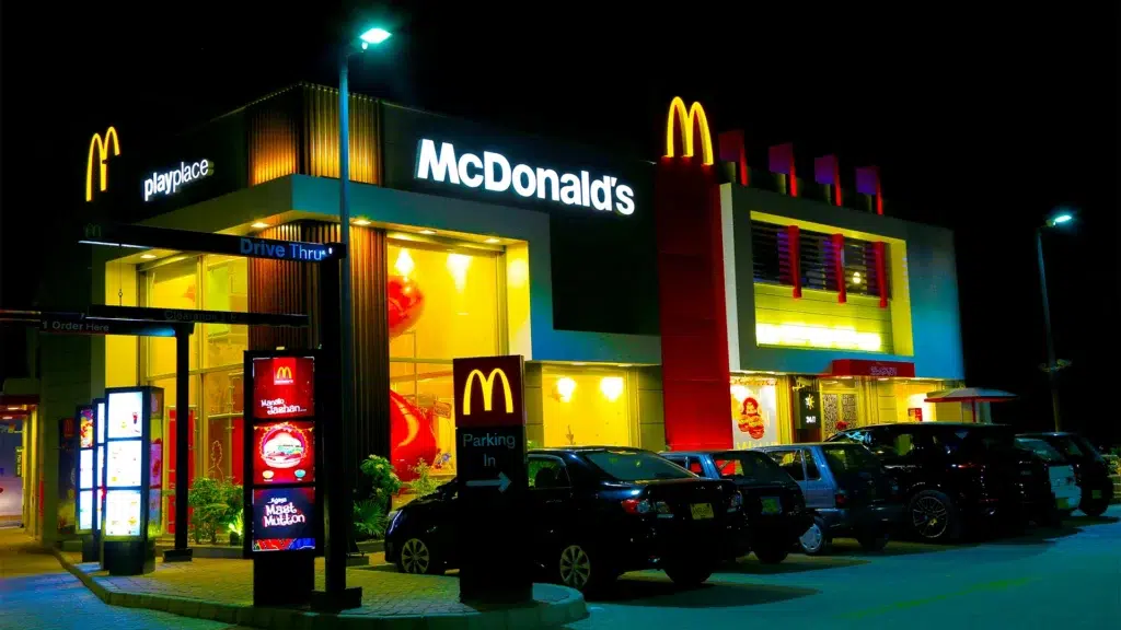 McDonald's restaurant exterior with illuminated golden arches and drive-thru at night