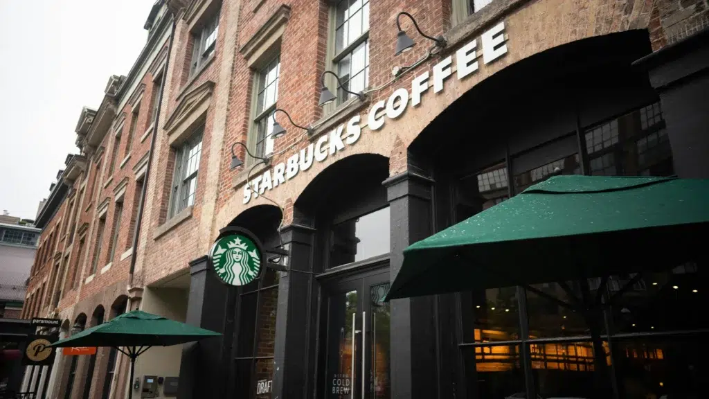 Starbucks Coffee store exterior with green umbrellas and signage on brick building