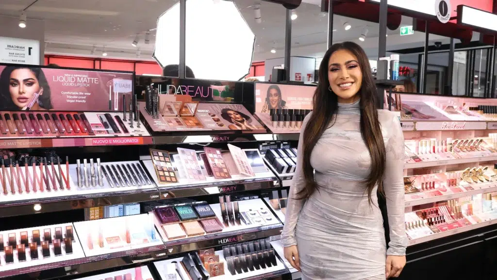 Huda Kattan standing in Huda Beauty retail display showing the founder who built a $1 billion beauty brand from a blog and regained full ownership in 2025