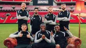 Sidemen members in black and white Adidas tracksuits posing at stadium for annual charity football match featuring KSI, Miniminter, Zerkaa, Behzinga, Tobjizzle, Vikstar and Harry W2S
