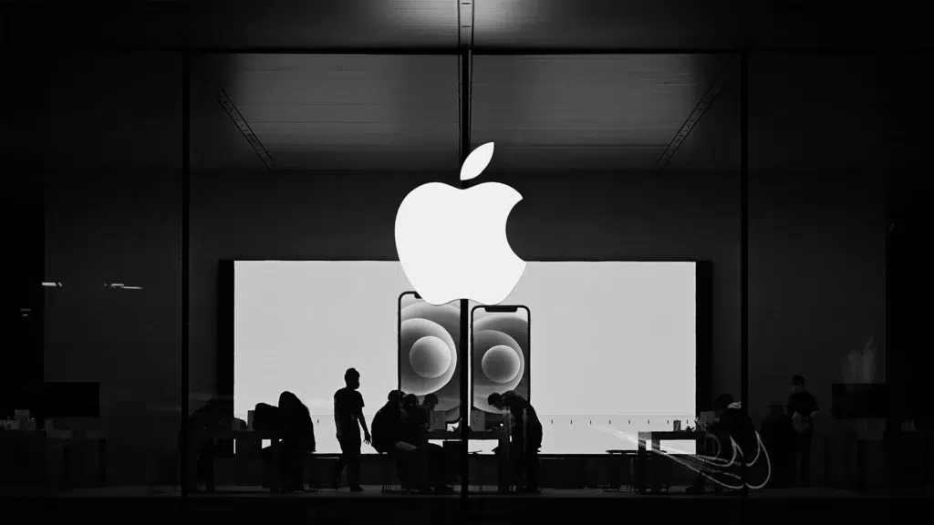 Apple store facade at night in black and white with silhouettes of customers and glowing Apple logo